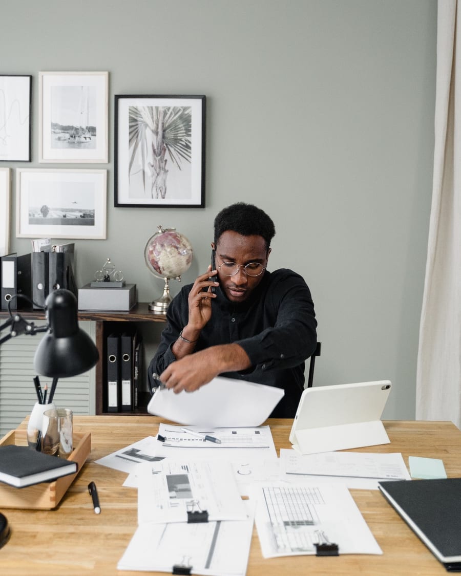 An agency owner on the phone, pulling a page from the reports spread across the desk